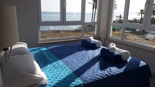 a bedroom with a bed with towels and windows at Periyiali Beach Sunset Suite A7 in Pervolia