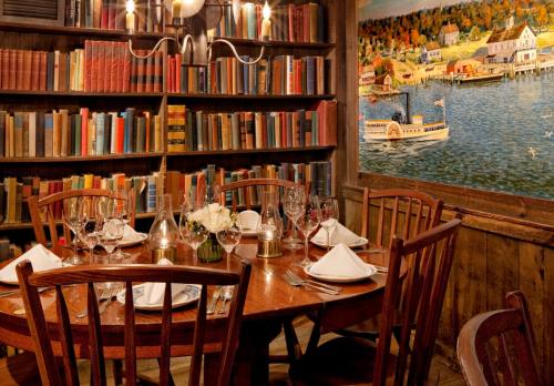 Essex的住宿－The Griswold Inn，图书馆里的一张木桌,里面摆放着椅子和书籍