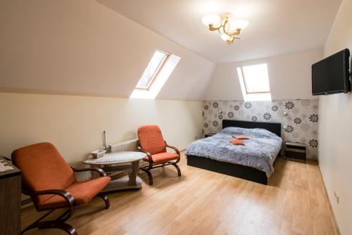 a bedroom with a bed and two chairs and a table at Holiday Home Ermine in Sigulda