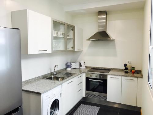 a white kitchen with a sink and a dishwasher at Apartamentos da Sé Catedral in Funchal