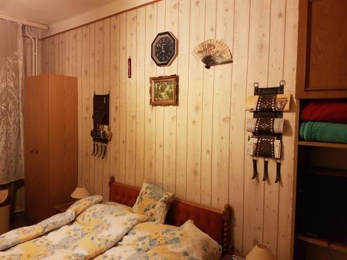 1 dormitorio con 1 cama y pared de madera en Jancsi és Juliska Vendégház, en Abaújszántó