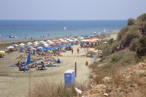 a beach with many umbrellas and people on the beach at Periyiali Beach Sunset Suite A7 in Pervolia