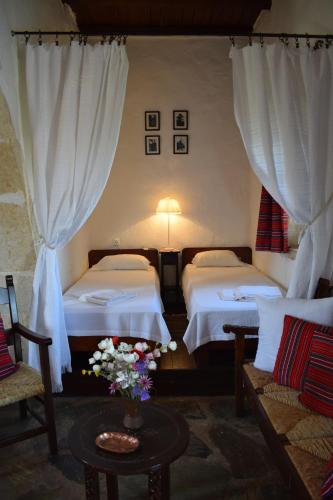 um quarto de hotel com duas camas e uma mesa com flores em Anna's Stone House em Megála Khoráfia