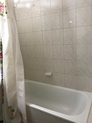 a white bath tub with a shower curtain in a bathroom at Amoblados Neuquen ALTO COMAHUE SHOPPING in Neuquén