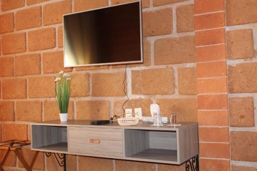 a tv on a brick wall with a table at Hotel Boutique La Herencia in Tequisquiapan
