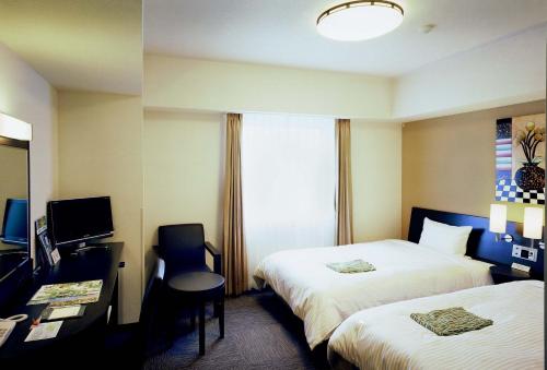 a hotel room with two beds and a desk at Hotel Route-Inn Ashikaga-2 in Ashikaga