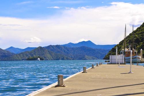 a dock on a body of water with a boat at Oxley's Waterfront Apartment in Picton