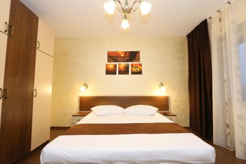 Un dormitorio con una gran cama blanca y una lámpara de araña. en Apartament Erika - by the beach, en Constanţa