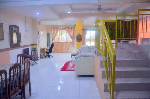 a living room with stairs and a couch and chairs at Homestay Mamasya Melaka in Melaka