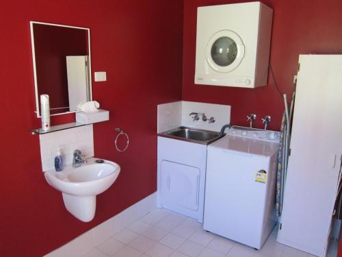 a red bathroom with a sink and a toilet at Neds Cabin in Amiens