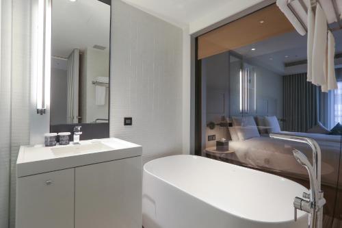 a white bathroom with a sink and a mirror at Greet Inn in Kaohsiung