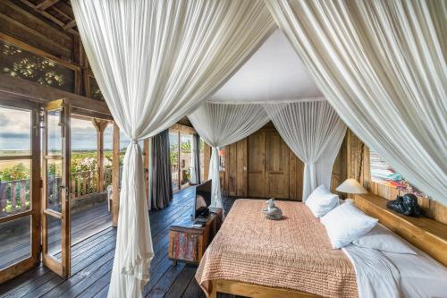 منتجع وفيلات ألامي البوتيكية  في تابانان: غرفة نوم بسرير مع مظلة