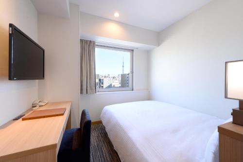 a hotel room with a bed and a desk and a window at Vessel Inn Ueno Iriya Ekimae in Tokyo