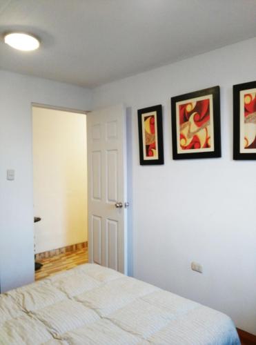 a bedroom with a bed and three paintings on the wall at White Hope Apartment in Lima