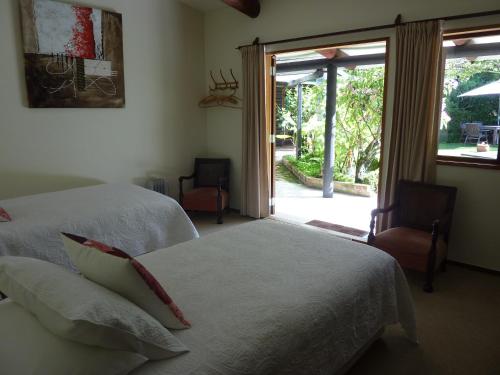 a bedroom with two beds and a sliding glass door at Thorold Country House in Thames