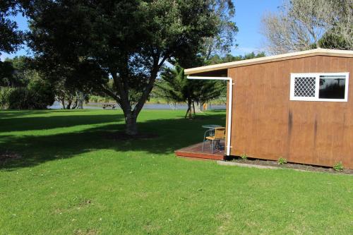 a small shed with a table and a tree at Urenui Beach Camp in Urenui