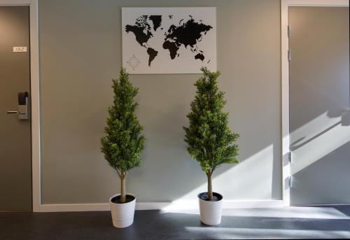 two trees in white pots in a room with a map at Hotell Eken Mölndal in Mölndal