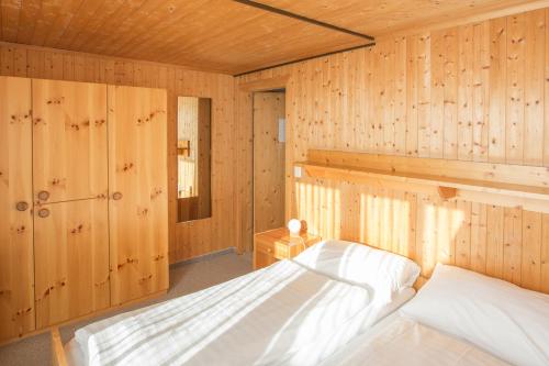 a bedroom with wooden walls and a bed in a room at Berghaus Nagens in Flims