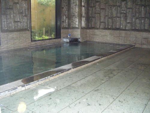 a swimming pool in a room with a tile floor at Hotel Route-Inn Nagaizumi Numazu Inter 1 in Nagaizumi