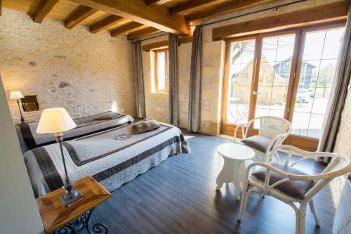1 dormitorio con 1 cama, mesa y sillas en Chambres d'Hôtes L'Oustralac, en La Chapelle-Aubareil