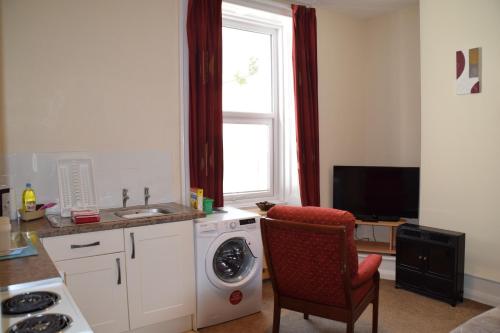 a kitchen with a washing machine and a window at Kittiwake House in Port Erin