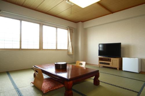 a living room with a table and a flat screen tv at Kojohama Onsen Hotel in Shiraoi