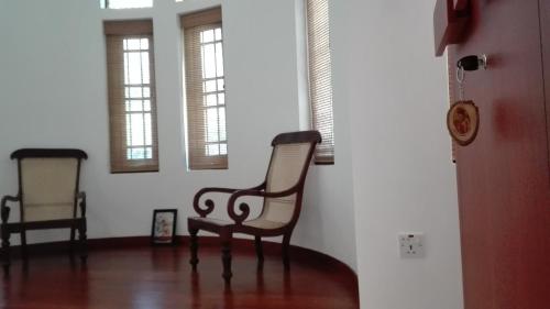 a living room with a chair and two windows at Crescent N Cocoon in Ambalangoda