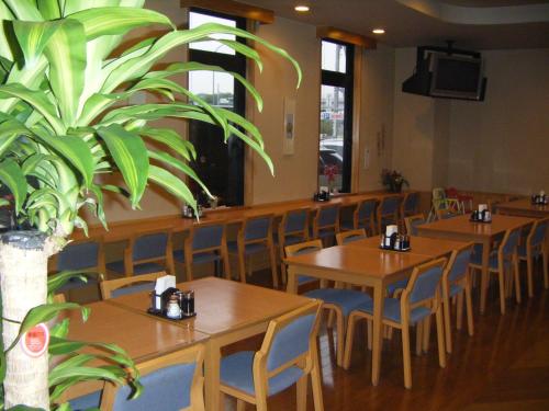 a restaurant with wooden tables and chairs and a potted plant at Hotel Route-Inn Nagaizumi Numazu Inter 1 in Nagaizumi