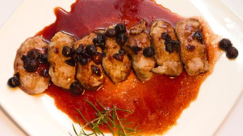 a plate of food with chicken with black beans and sauce at Hospedium Hostal Restaurante El Mirador de Atienza in Atienza