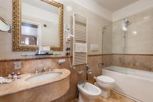 a bathroom with a sink and a toilet and a mirror at Hotel Ca' dei Conti in Venice