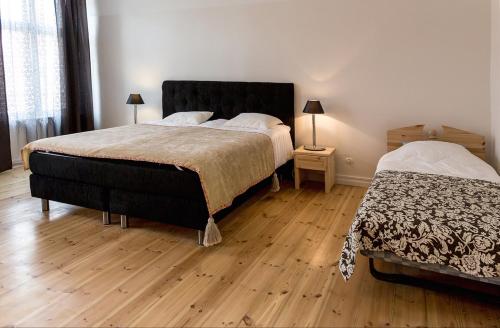 a bedroom with two beds and a wooden floor at Aia Vacation Apartment in Pärnu