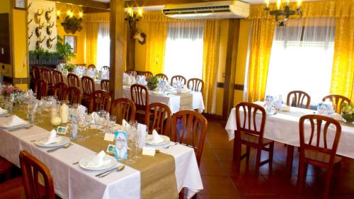 a dining room with tables and chairs with white tablecloths at Hospedium Hostal Restaurante El Mirador de Atienza in Atienza