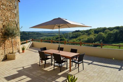 a wooden table with chairs and an umbrella on a patio at Aux Volets Bleus Chez Mark & Sylvie in Rouffignac Saint-Cernin