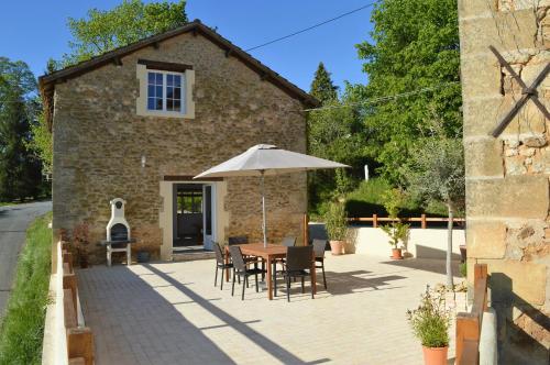 a table with an umbrella in front of a building at Aux Volets Bleus Chez Mark & Sylvie in Rouffignac Saint-Cernin