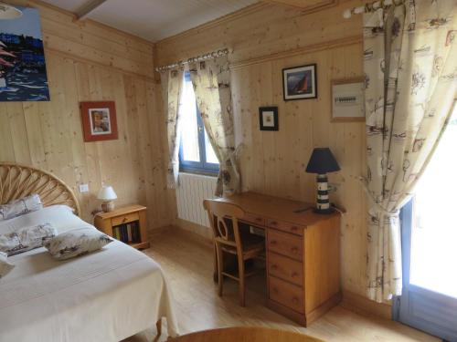 a bedroom with a bed and a desk and a window at Les Petites Aunettes in Vaubadon