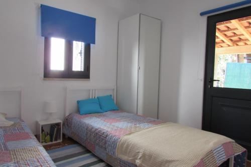 a bedroom with a bed with blue pillows and a window at Casas da Nazare in Ponte de Lima