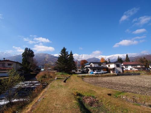 a field with houses and mountains in the background at Nori's Sharehouse Hakuba in Hakuba