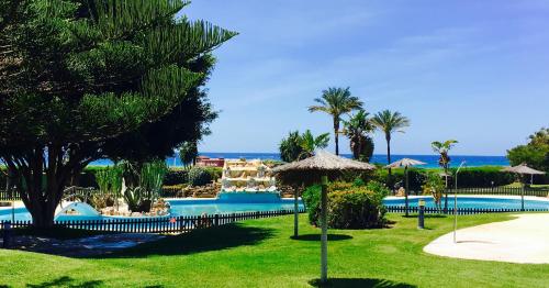 Una piscina en un resort con palmeras y el océano. en Atico En Atlanterra Playa, en Zahara de los Atunes