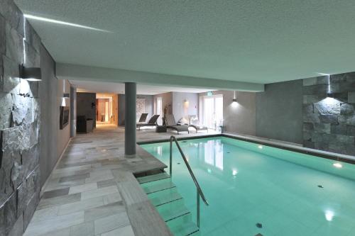 a swimming pool in a house with a living room at Hotel Strand am Königshafen in List