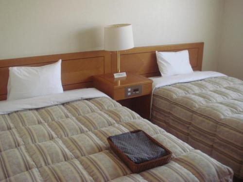 a hotel room with two beds and a lamp on a table at Hotel Route-Inn Fukui Owada in Fukui
