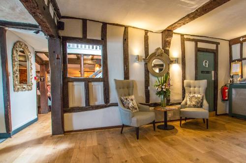a room with two chairs and a table and a mirror at The Saracens Head Hotel - The Coaching Inn Group in Great Dunmow