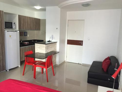 a kitchen and a living room with a table and red chairs at Studio Everest Flats in Recife