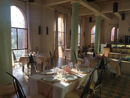 a dining room with tables and chairs and windows at Kasbah Titrit & Spa in Aït Ben Haddou