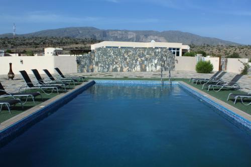 a large swimming pool with chairs and a building at Jebel Shams Resort منتجع جبل شمس in Dār Sawdāʼ