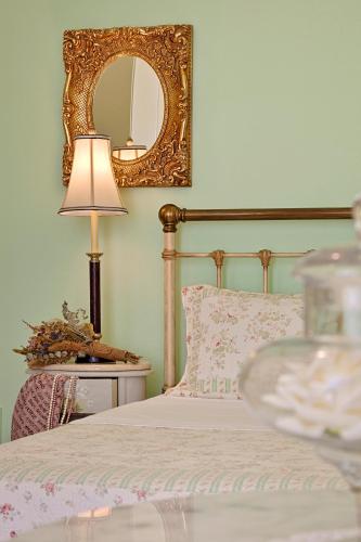a bedroom with a bed with a mirror and a lamp at Antouanetta Apartments in Ermoupoli