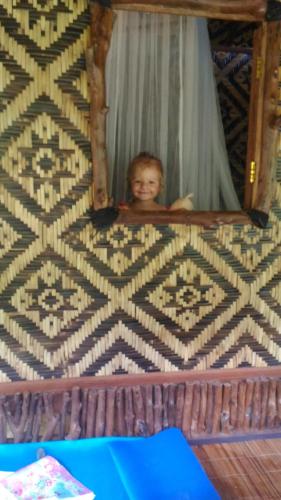 a small child is peeking out of a bed at Bali Jungle Resort in Tegalalang