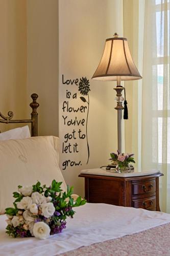 a bedroom with a bed with a lamp and flowers at Antouanetta Apartments in Ermoupoli