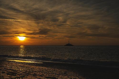 a sunset on the beach with the ocean and a lighthouse at Villa Moby Dick in Mitikas