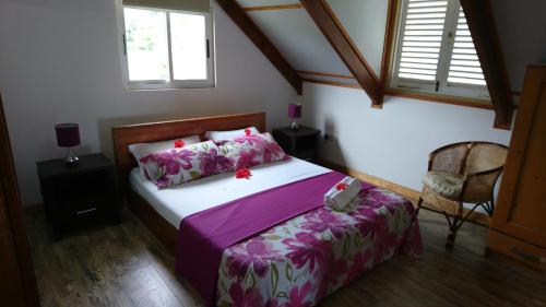 a bedroom with a bed with purple sheets and flowers at Skyline View in Bel Ombre