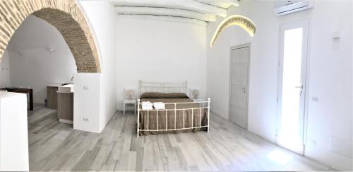 a bedroom with a bed in a white room at Mandralisca Garden in Cefalù